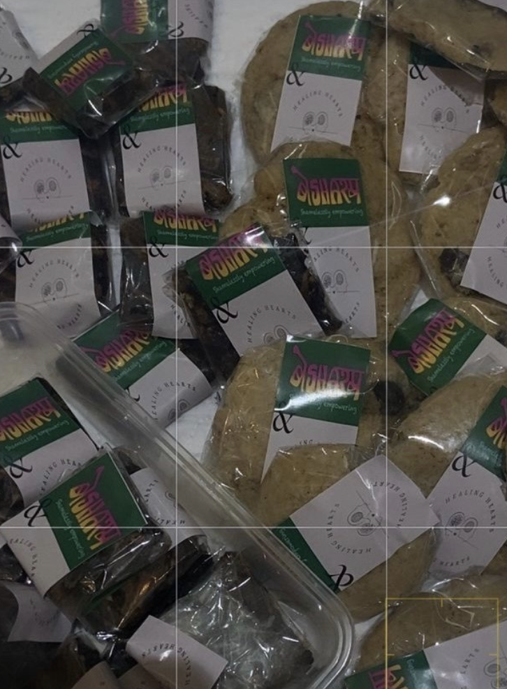 Individually wrapped brownies and chocolate-chunk cookies from the bake sale, sealed with green Besharam label bands and a Healing Hearts illustration.