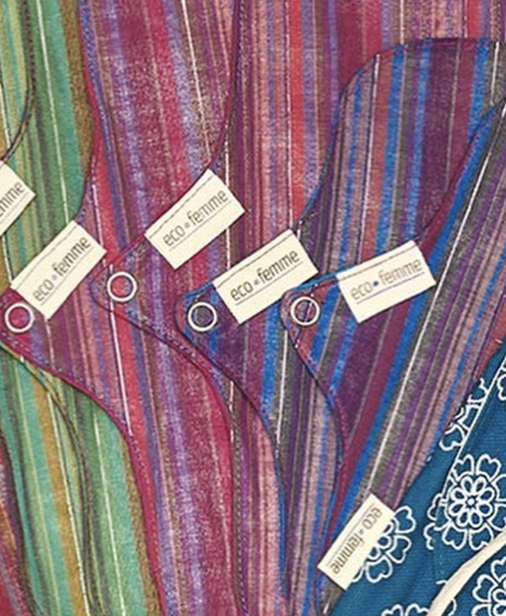 A fan of reusable Eco Femme cloth sanitary pads in multicoloured striped fabric, with snap-button wings and eco femme labels.