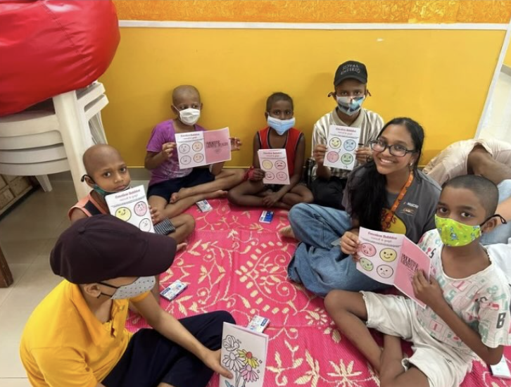 Children holding emotion worksheets with a Healing Hearts facilitator at St. Jude India ChildCare Centres