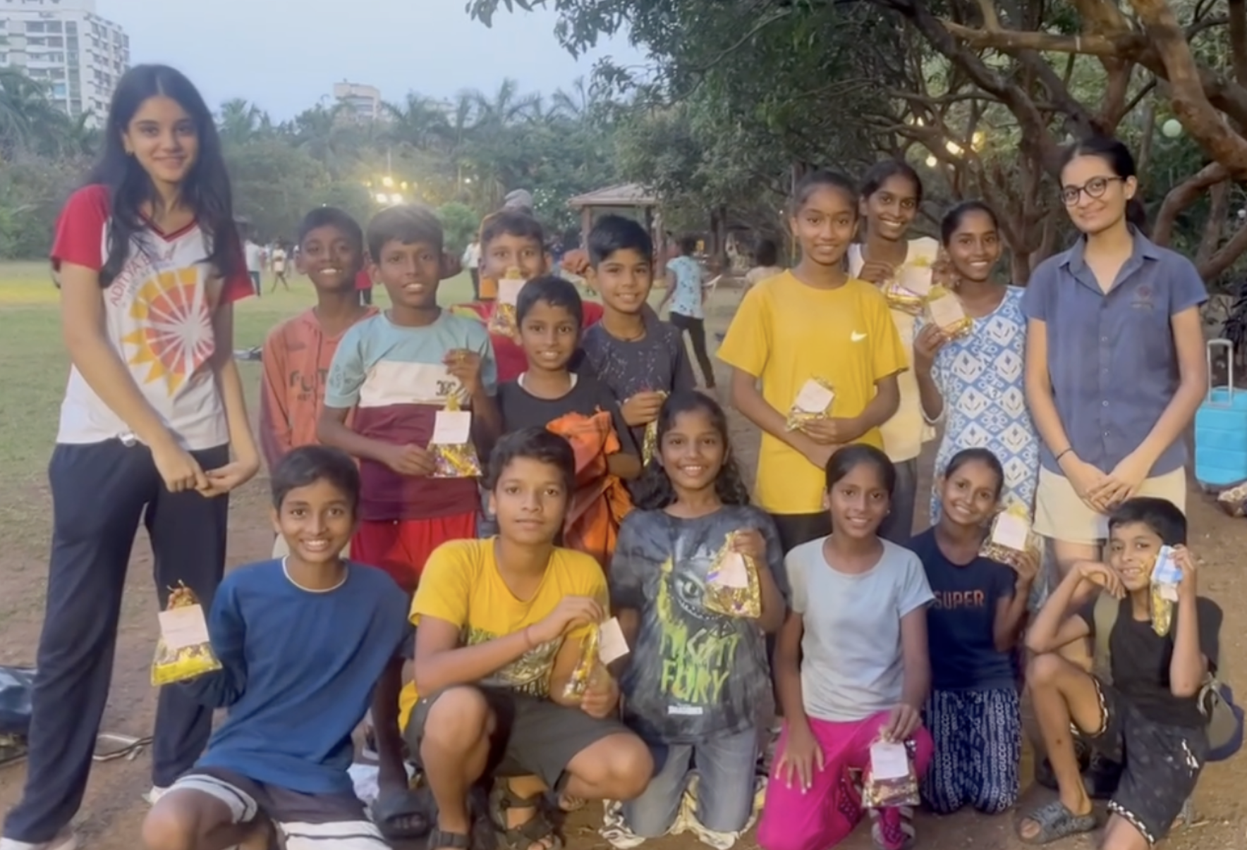 Group photograph with children holding care bags at Down To Earth NGO